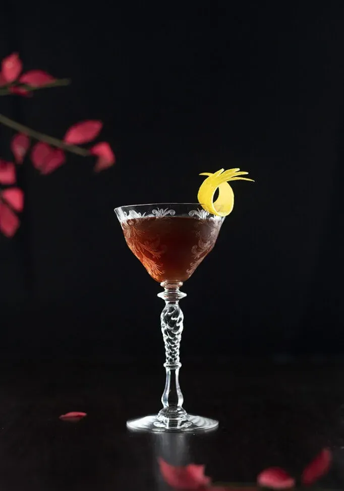 brauner Cocktail neben roten Blättern' title=