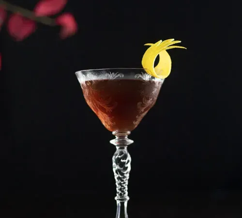 Brauner Cocktail in einem Stielglas mit einer Zitronennote' title=