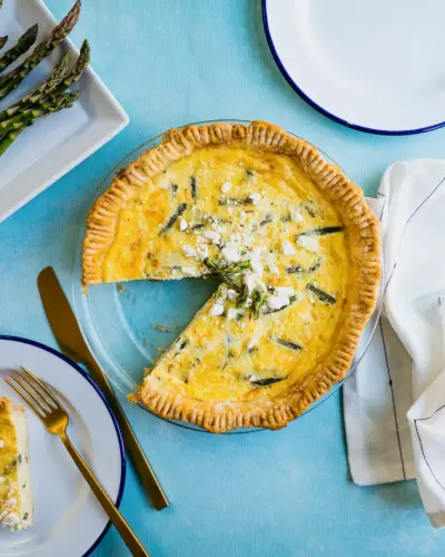 Spargelquiche mit ausgeschnittenen Spargeln und gedecktem Tisch.