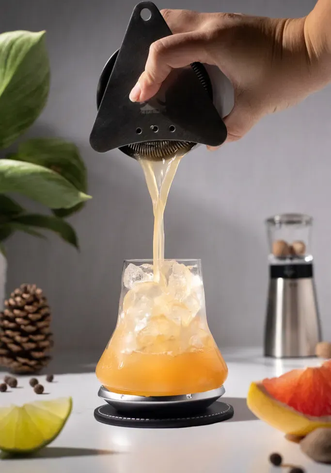 filtrer le cocktail dans un verre à whisky fantaisie rempli de glace.' loading='lazy' title=