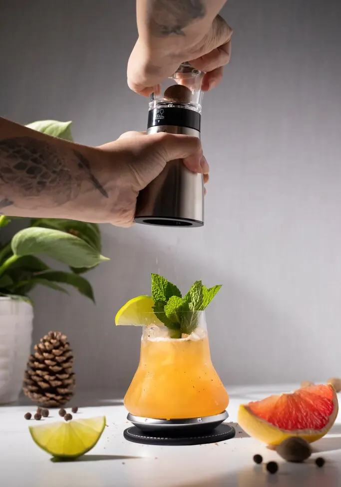 râper de la muscade sur un cocktail tropical avec un moulin à noix de muscade Madras Peugeot Saveurs.' title=