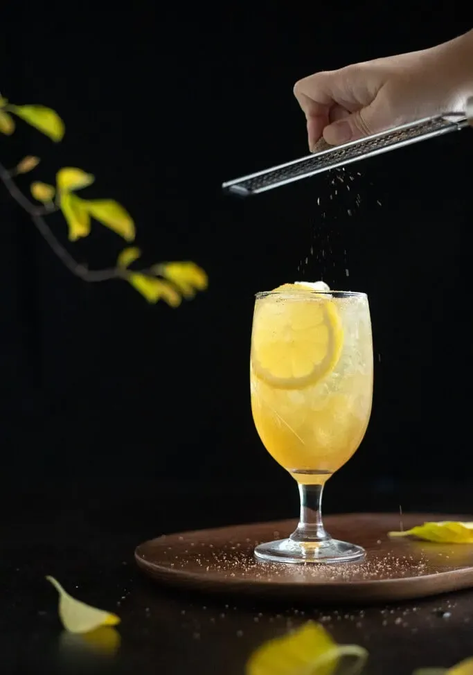 ucierając gałkę muszkatołową nad szklanką Fish House Punch' title=