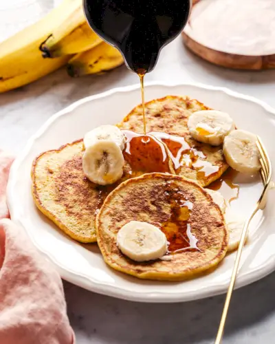 Panquecas de banana com 3 ingredientes e xarope de bordo por cima.