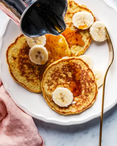 Panquecas de banana com bananas fatiadas e calda.