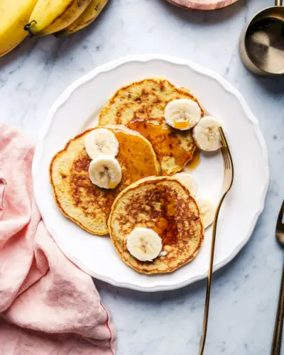 Panquecas de banana com 3 ingredientes no lugar com um garfo.