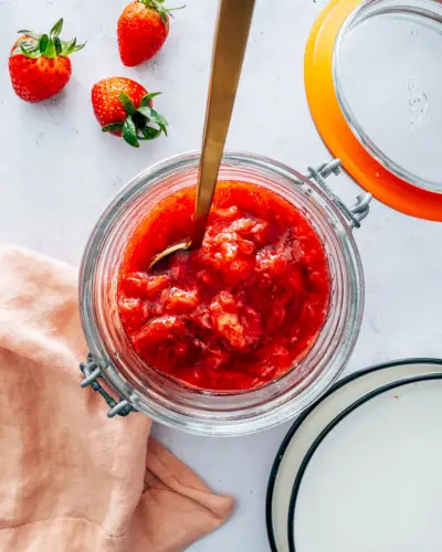 Compote de fraises en pot avec cuillère et fraises.
