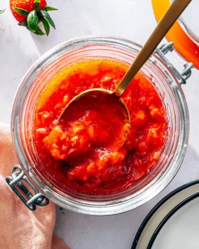 Compote de fraises dans un pot avec une cuillère en or.