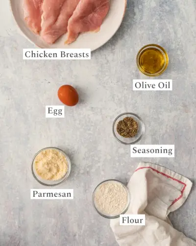 Poulet en croûte de parmesan tranché sur une assiette avec du persil et du citron.