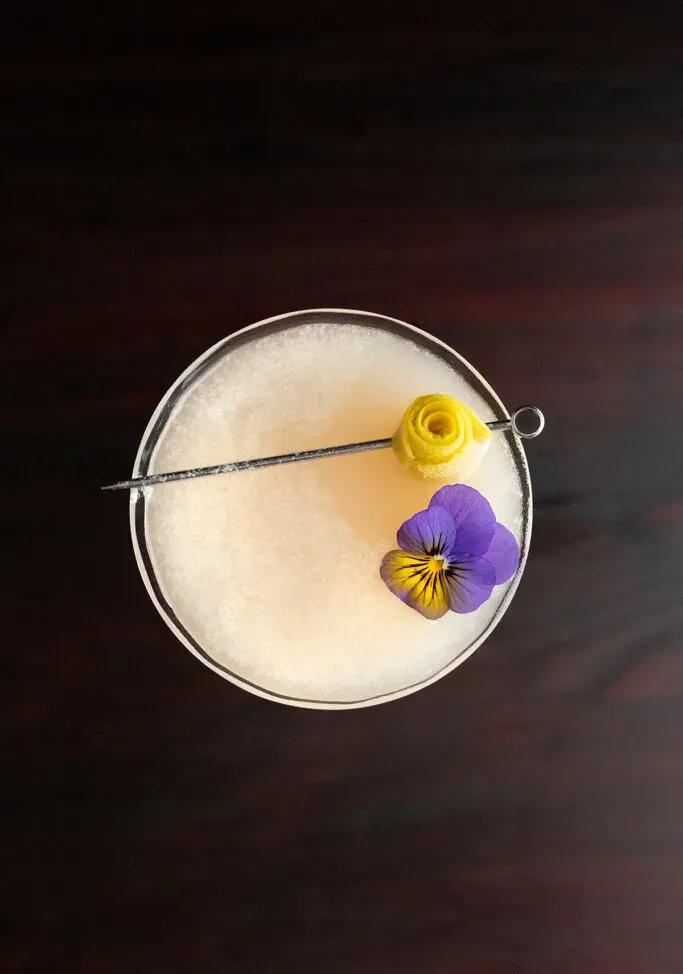 칵테일에 떠 있는 식용 비올라 꽃의 머리 위 전망.' title=