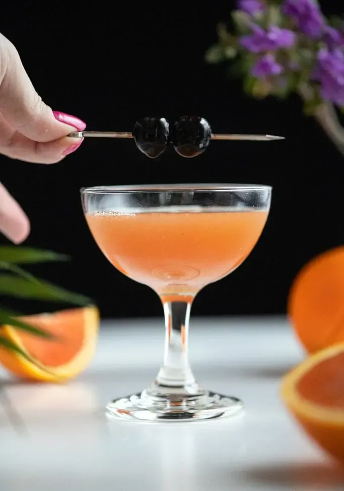 enfeitando um coquetel de laranja com duas cerejas em uma picareta.' loading='lazy' title=