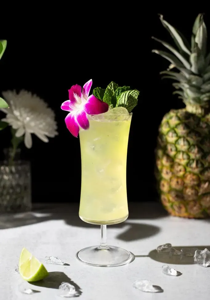 Koktejl Missionary’s Downfall v hurikánové sklenici s orchidejí.' title=