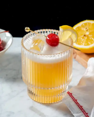 Bebida Rum Sour em copo de coquetel com enfeite de cereja e limão