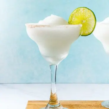 Margarita congelada em copo com borda de sal e rodela de limão.