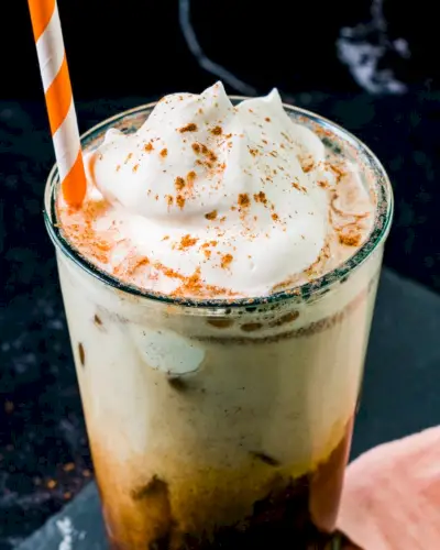 Iced Pumpkin Spice Latte vo vysokom pohári s oranžovou slamkou