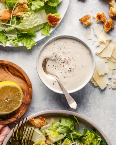 Ricetta del condimento per insalata Caesar fatto in casa in una ciotola con cucchiaio.