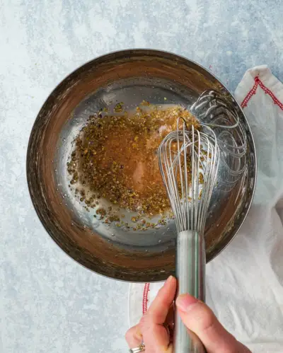 Condimento per insalata greca Passaggio 1: sbatti l'aceto di vino rosso, il limone, Digione e le erbe aromatiche.
