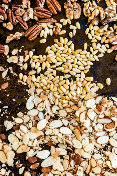 Comment griller des noix au four : amandes, pignons de pin et noix sur une plaque à pâtisserie.
