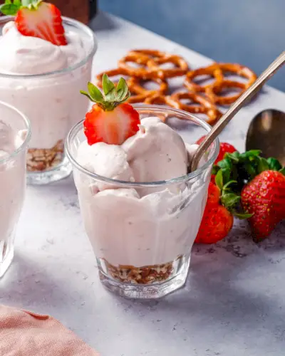 Erdbeermousse in einer Tasse mit Löffel und Erdbeergarnitur.