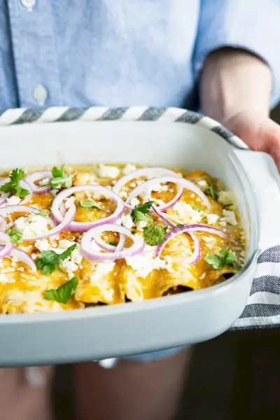 Mãos segurando enchiladas na panela