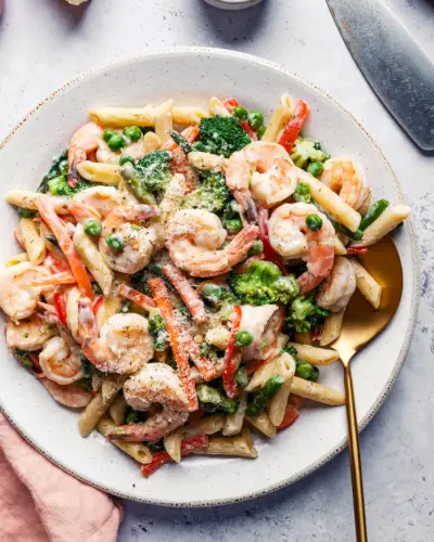 Gamberi Primavera in ciotola con verdure colorate e salsa cremosa.