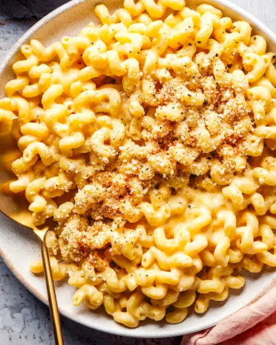 Macaroni au fromage cottage et fromage dans un bol avec une cuillère et garni de chapelure.