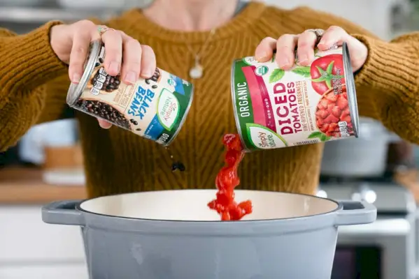 Despejando feijão e tomate em uma panela