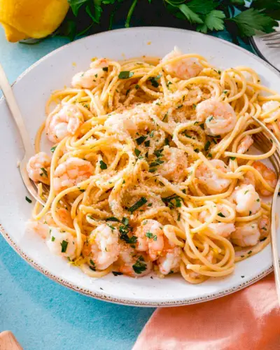 Pasta di gamberi all'aglio sul piatto con contorno di parmigiano e prezzemolo.