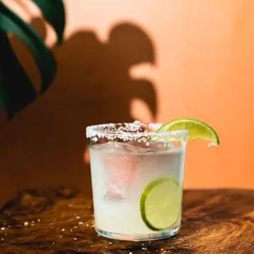 Cocktail de tequila en verre avec quartier de citron vert et bord de sel.