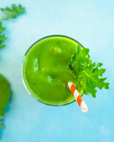 Recette de smoothie au chou frisé dans un verre avec garniture de paille et de feuilles de chou frisé.