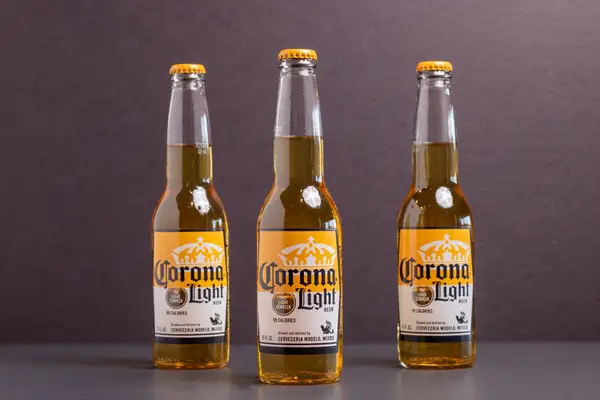 three bottles of corona light beer on gray background