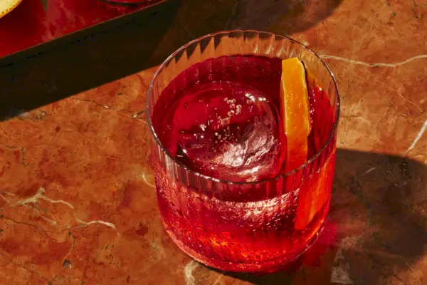 Un negroni sans alcool avec une tranche d'orange et un gros glaçon.