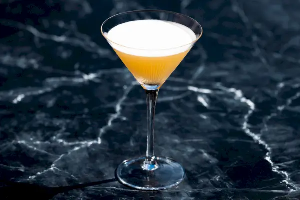 Französischer Blonde-Cocktail in einem Martini-Glas vor einem dunklen Schiefermarmorhintergrund