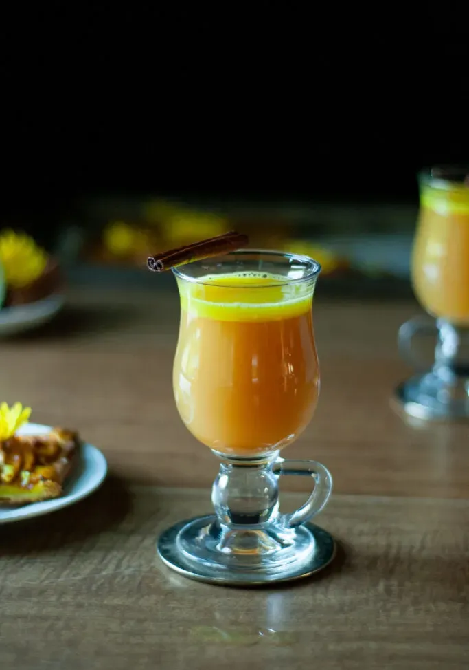 Heißer goldener Cocktail mit einer Zimtstangengarnitur.' title=