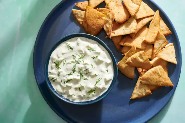 Uma tigela de molho tzatziki de pepino e endro, servida com chips de pão árabe