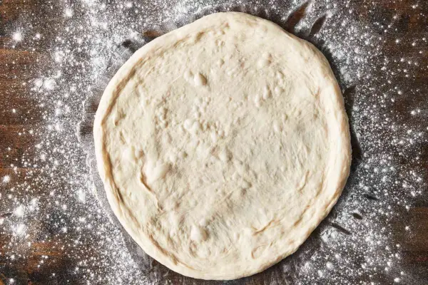 pasta per pizza rotonda su una superficie leggermente infarinata