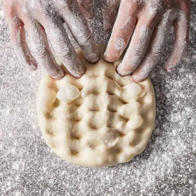 dita che agganciano l'impasto della pizza