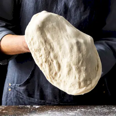stendendo delicatamente l'impasto della pizza