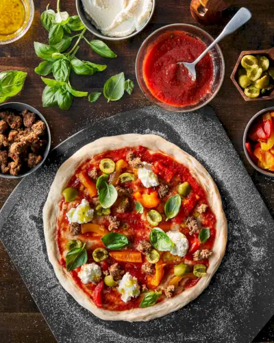 condire una pizza con ricotta, olive, salsiccia