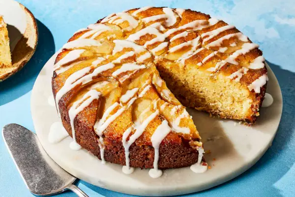 Um bolo de maçã de cabeça para baixo regado com cobertura e servido em uma travessa