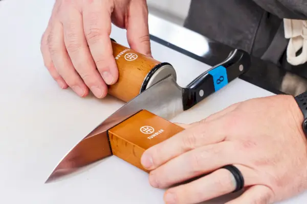 אדם משתמש ב-Tumbler The Original Rolling Knife Sharpener כדי להשחיז סכין