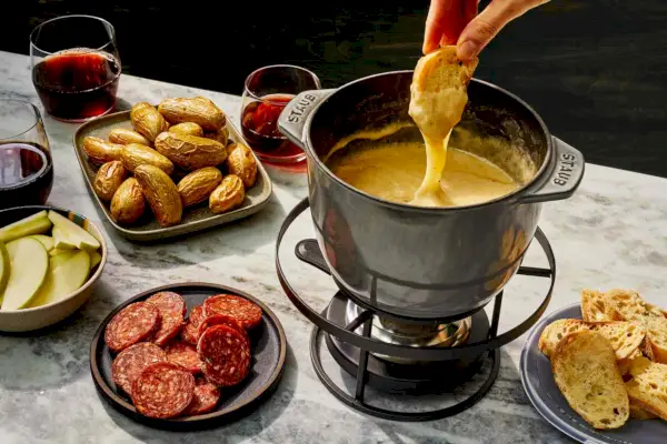 Fondue z sera szwajcarskiego z dipami takimi jak chleb, ziemniaki, salami, jabłka