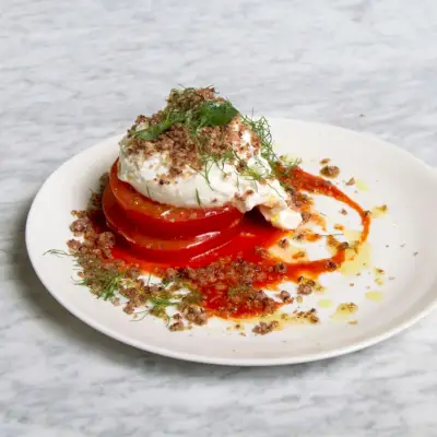 Na talerzu porcja steku z pomidorów i sałatki burrata z oliwkami Streusel.