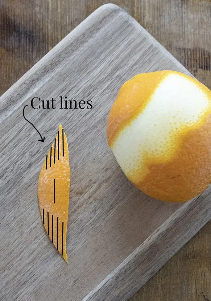Close de casca de laranja com linhas pretas sobrepostas para indicar onde fazer cortes para um enfeite sofisticado' title=