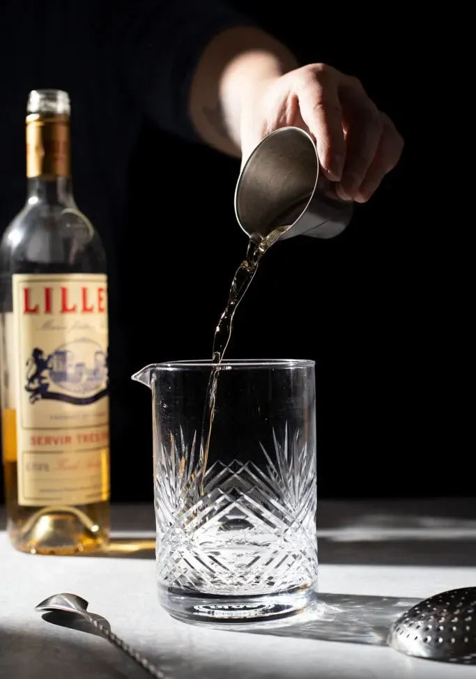 versare Lillet Blanc da un jigger in un mixing glass.' title=