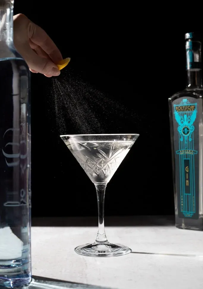 spremendo una scorza di limone su un martini.' title=