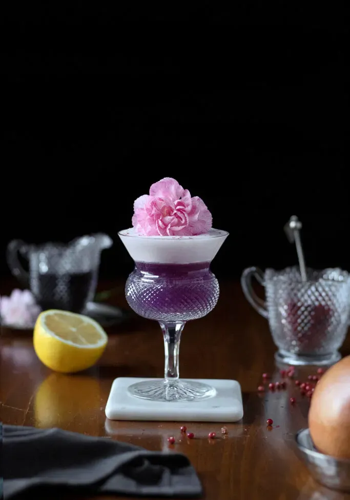 coquetel roxo ao lado de pimenta rosa e toranja.' loading='lazy' title=