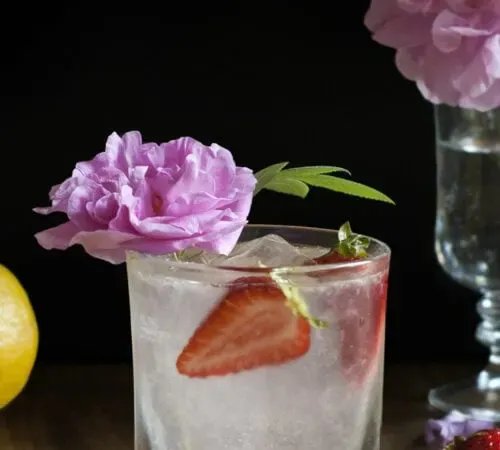 copo de pedras com limonada e fatias de morango decoradas com uma rosa.' loading='lazy' title=