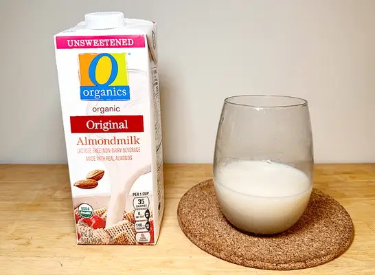 O organics almond milk container next to a glass of it