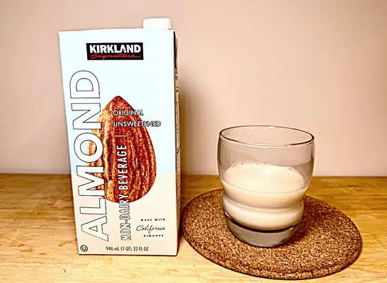 a container of kirkland almond milk next to a glass