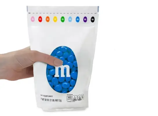 a hand holding a bag of blue m & m